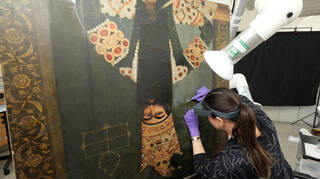 a conservator looks closely at a painting